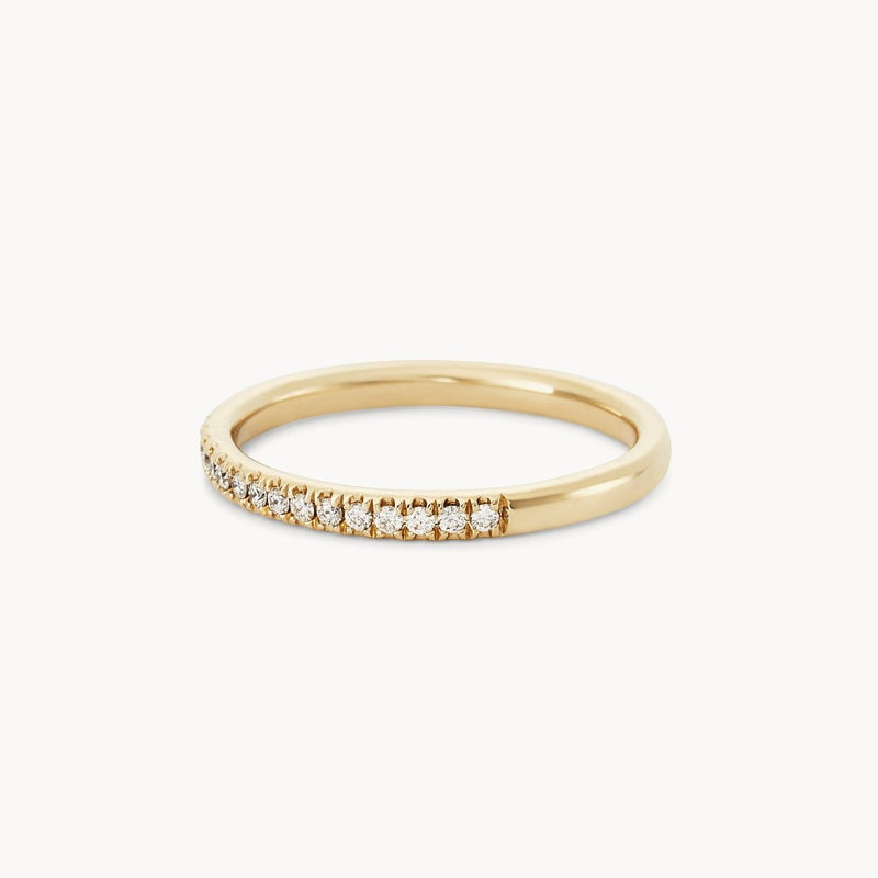 The Endalaus II ring by beloved by bluboho in 14k yellow gold features a row of small, sparkling white diamonds embedded along the upper half. Set against a plain white background, this delicate piece highlights elegance and simplicity.