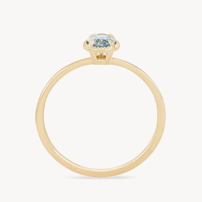 Introducing the "golden glow one-of-a-kind ring" by *beloved by bluboho* - a delicate 14k yellow gold ring showcasing a stunning cyan green oval sapphire in a minimalist prong setting, viewed from the side. The band is thin and polished, enhancing the elegance of this exquisite piece.