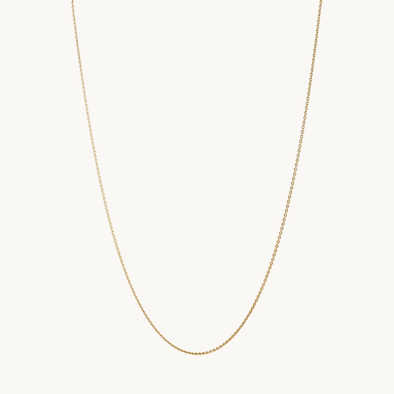 The classic cable chain - 10k yellow gold by bluboho is a delicate necklace featuring a minimalist design with fine, interlocking links. The chain forms a gentle curve and is suspended against a plain white background, highlighting its elegant simplicity.