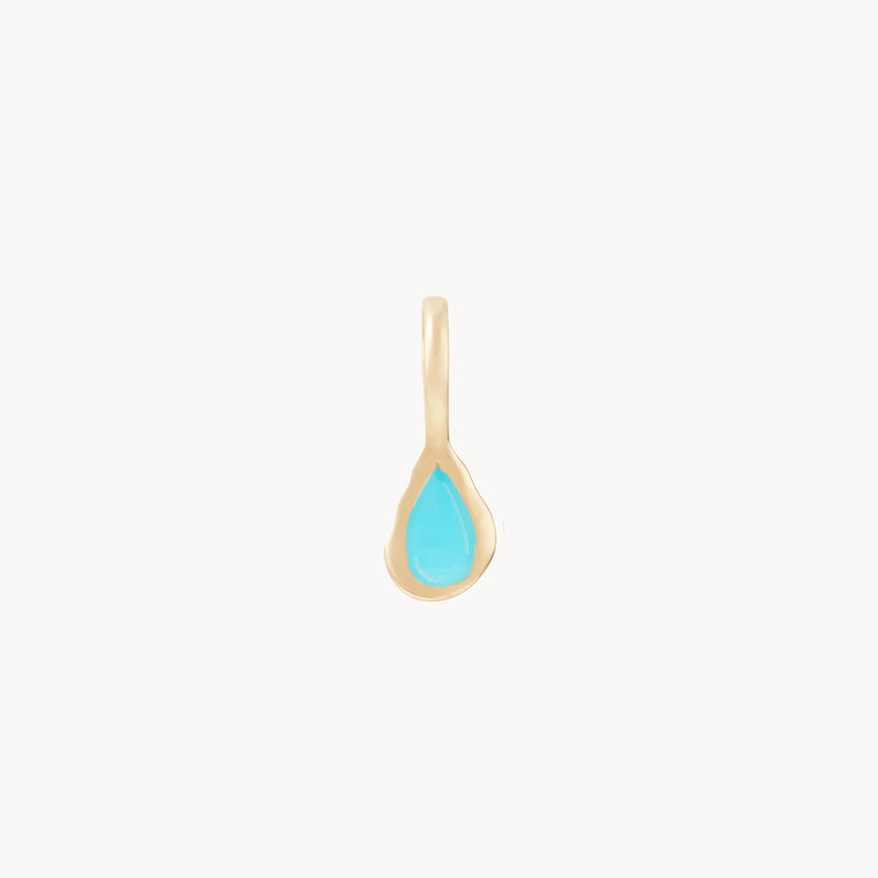 The "pear turquoise december mood birthstone charm" by bluboho features a delicate teardrop-shaped turquoise stone at its center, set in 10k yellow gold. The minimalistic design exudes elegance and simplicity, making it a versatile accessory for any occasion. The background is plain white.