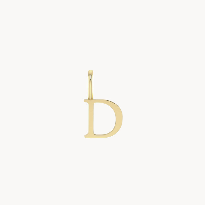 A simple gold pendant shaped like the uppercase letter "D." The letter is sleek and smooth, with a small loop at the top for attaching to a necklace or bracelet. The background is plain, placing full focus on the letter charm - 10k yellow gold by bluboho.