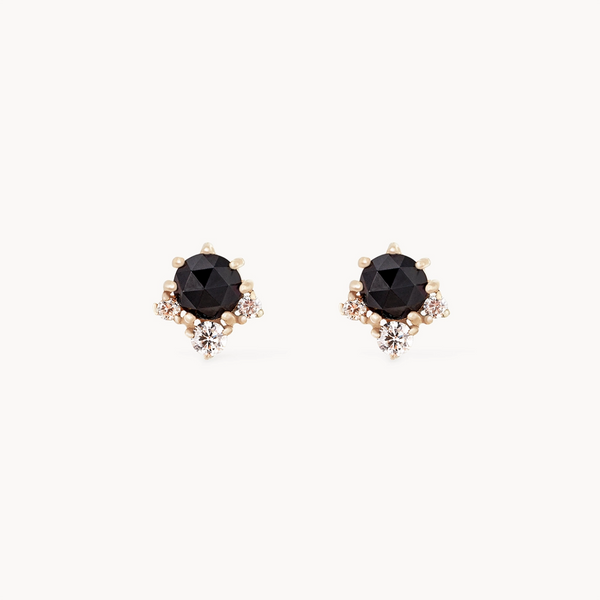 The "Full Moon Glow Diamond Black Onyx Earring" by Bluboho features faceted black onyx stones set in a refined 14k yellow gold setting. Each earring is adorned with three small diamonds around the main black onyx, adding a touch of sparkle and sophistication against a plain white background.