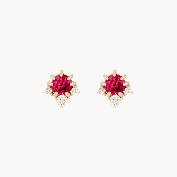 The full moon glow diamond ruby earrings by bluboho feature a central, vibrant ruby encased in 14k yellow gold, with small, sparkling diamonds arranged around the ruby center, creating a stylish and luxurious design.