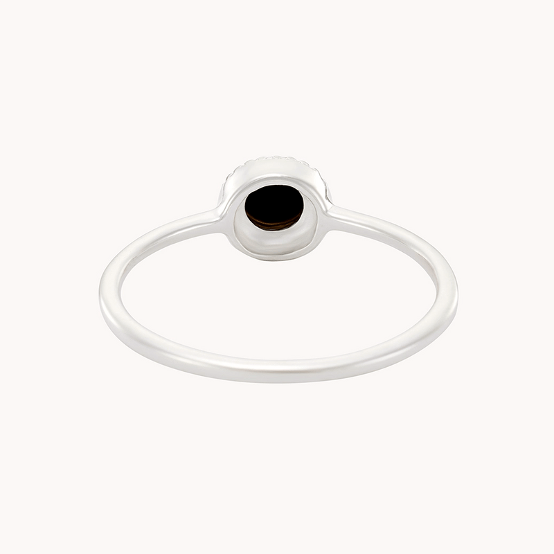 A minimalist silver ring with a thin band, featuring a small, round mother of pearl in black set in a simple bezel setting. The focus is on the ring's profile, showcasing its delicate design against a plain white background. This exquisite piece is the "full moon dark mother of pearl ring silver" by bluboho.