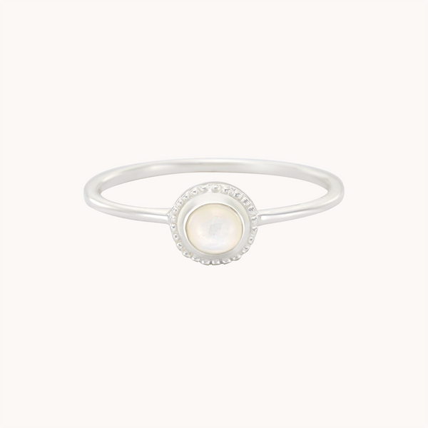 The "Full Moon Light Mother of Pearl Ring Silver" by Bluboho is an exquisite piece, showcasing a central round mother of pearl gemstone surrounded by a petite halo of tiny diamonds. The slender and minimalist band enhances the sophisticated charm of the mother of pearl and diamond accents.