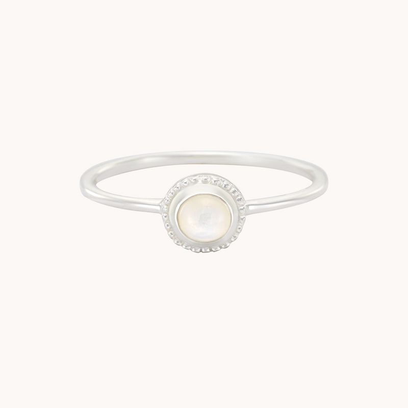 The "Full Moon Light Mother of Pearl Ring Silver" by Bluboho is an exquisite piece, showcasing a central round mother of pearl gemstone surrounded by a petite halo of tiny diamonds. The slender and minimalist band enhances the sophisticated charm of the mother of pearl and diamond accents.