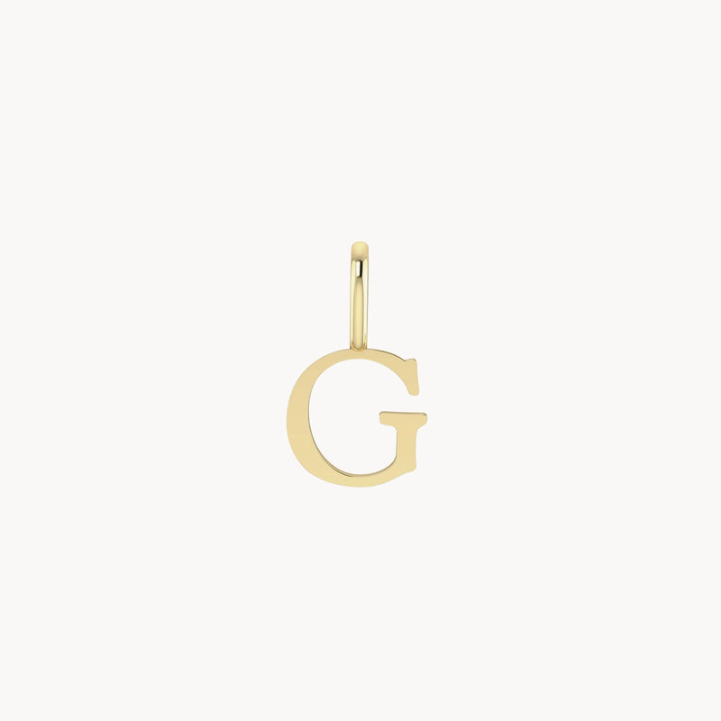 A letter charm - 10k yellow gold in the shape of the letter "G." The charm has a small loop at the top for attaching to a necklace or bracelet. The design is sleek and polished, set against a plain white background. This elegant piece is brought to you by bluboho.