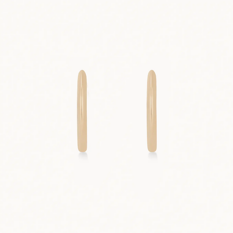 A pair of simple, thin, 14k yellow gold hoop earrings set against a plain white background. The bluboho dagger medium hoop earrings have a smooth, shiny finish and are positioned vertically side by side.