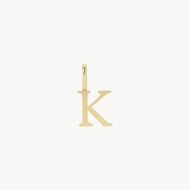 A bluboho letter charm - 10k yellow gold, in the shape of the letter "K", designed to be attached to a necklace or bracelet. The charm is simple, with a smooth finish, and is hanging from a small loop. The background is white.