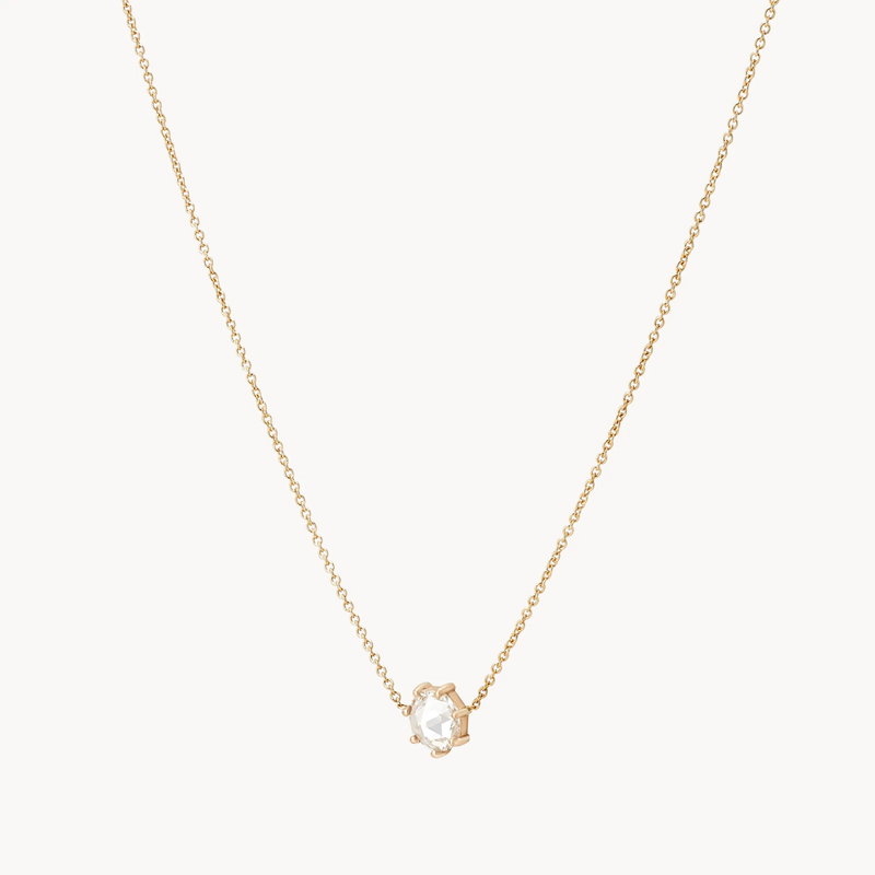 The large supernova necklace by bluboho is a delicate piece with a fine chain, featuring a small, clear gemstone pendant set in a simple four-prong setting. The elegant design emphasizes the single, faceted gem, making it the focal point against the plain white background.