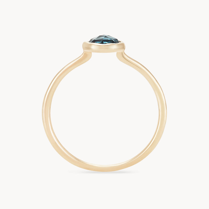 Introducing the london blue topaz mini mood ring by bluboho: a 10k yellow gold ring with a minimalist design, featuring a single round blue topaz gemstone held by a thin band. The gemstone is prominently displayed at the top of the ring in a raised setting that allows light to pass through, all set against a white background.