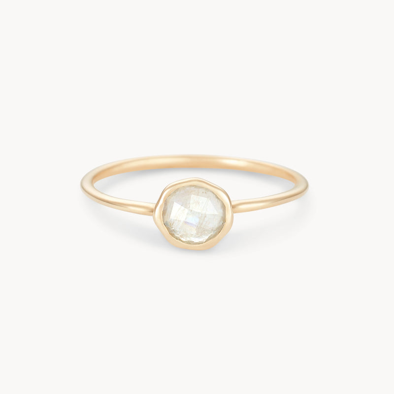 A delicate moonstone mini mood ring - 10k yellow gold, moonstone with a round, faceted clear gemstone in the center, set within a simple bezel setting by bluboho, displayed against a white background. The band is thin and elegant, adding to the overall minimalist design of the ring.