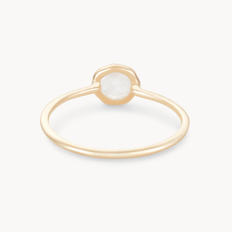 A delicate gold ring featuring a single, rough-cut white gemstone set in a minimalist bezel setting. The thin gold band is simple and elegant, complementing the subtle, natural beauty of the stone. The background is plain white. This exquisite piece is the moonstone mini mood ring - 10k yellow gold, moonstone by bluboho.