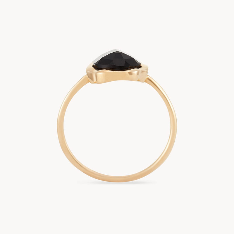 Introducing the black onyx mood ring by bluboho, crafted in 14k yellow gold. This minimalist design features a slender band with a striking black triangular gemstone at its center. The onyx is elegantly set in a subtle bezel, showcasing its faceted surface beautifully against the soft off-white background.