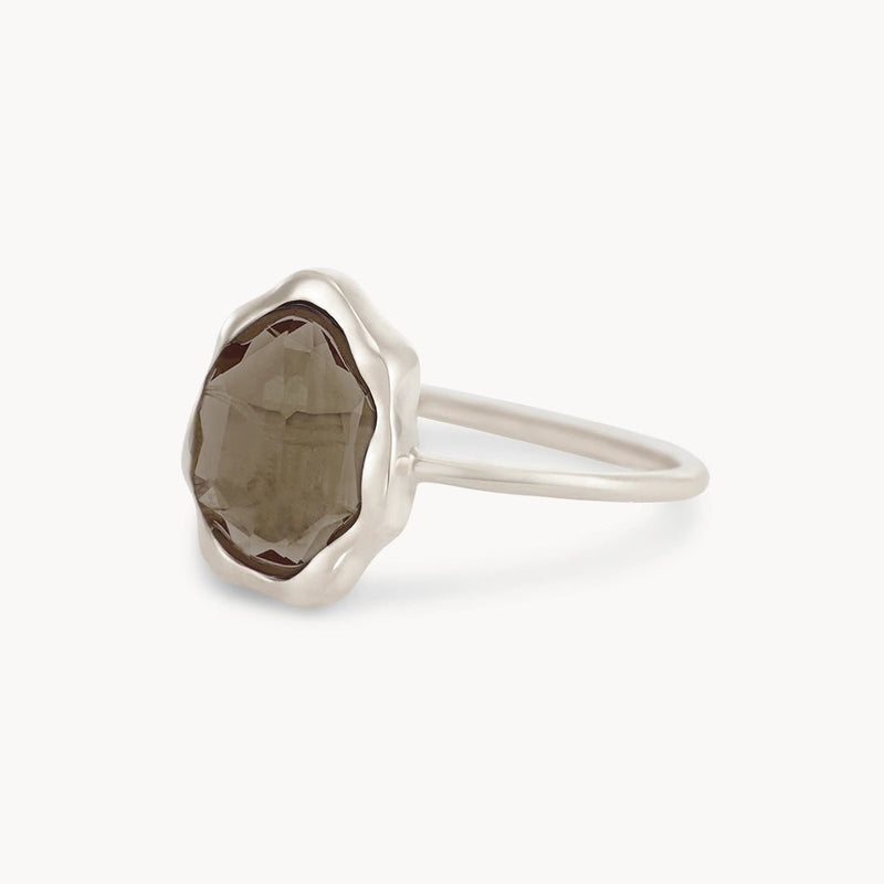 The smoky quartz mood ring by bluboho showcases a dark, faceted smoky quartz gemstone encased in an elegant wavy, scalloped bezel setting. The sterling silver band is smooth and polished, creating a sleek contrast with the textured stone. This minimalist design highlights the natural beauty of the gem.