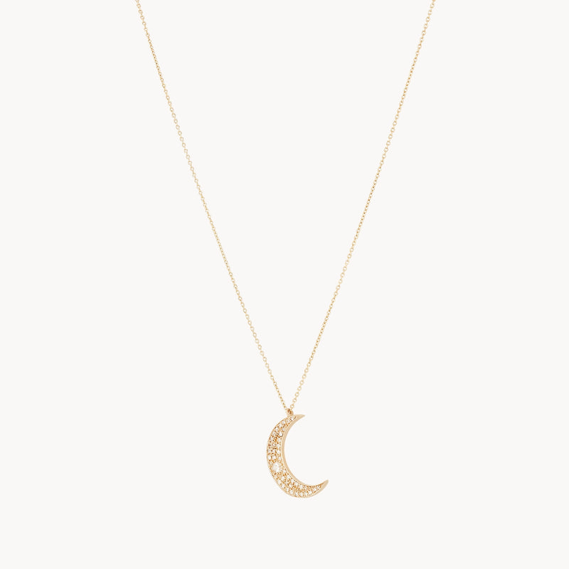 The Moonlight Crescent Diamond Necklace by bluboho features a delicate thin gold chain adorned with a crescent moon pendant encrusted with small, sparkling diamonds. The centrally hanging moon pendant adds a touch of elegance and shine to this exquisite piece.