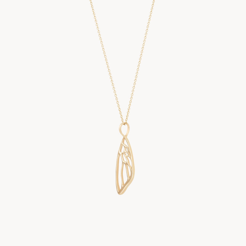 The butterfly wing charm by bluboho is a delicate necklace crafted from 10k yellow gold, featuring a fine chain and a pendant designed to resemble a stylized wing. The intricate openwork pattern of the pendant adds an airy and elegant touch to this beautiful piece.