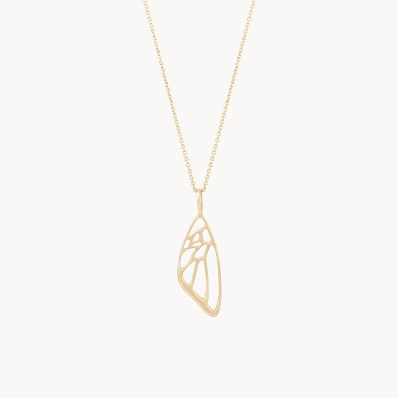 A delicate bluboho necklace in 10k yellow gold features a butterfly wing charm with an artistic, abstract design. The pendant hangs from a thin gold chain with small, evenly spaced links, creating an elegant and minimalist piece of jewelry.