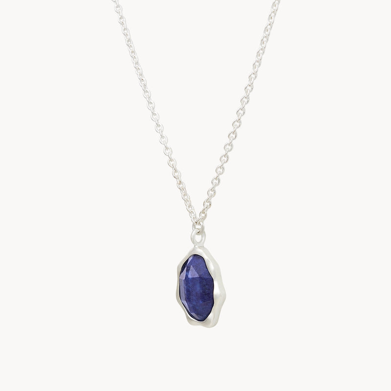 A lapis lazuli mood necklace silver - sterling silver, lapis lazuli by bluboho features a delicate chain and a pendant with a rough-cut, deep blue gemstone encased in a silver setting. The design is elegant and minimalist.