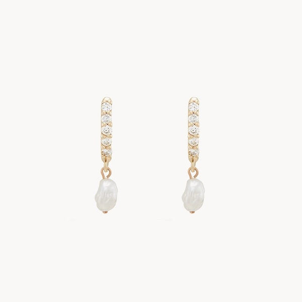 A pair of small gold hoop earrings from bluboho, each featuring a row of sparkling diamonds. Hanging from each hoop is a single irregularly shaped pearl, adding an elegant touch to the simple yet sophisticated design. The background is plain white. This exquisite piece is the "inner light diamond pearl earring - 14k yellow gold".