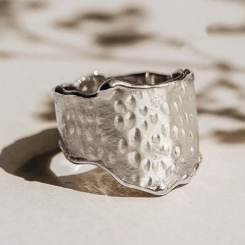 The sweetness of honey ring silver - sterling silver by bluboho rests on a light background, showcasing its textured, handcrafted design with an uneven surface and organic shape. The ring features small, indented dot patterns and a slightly wavy edge, casting a soft shadow.