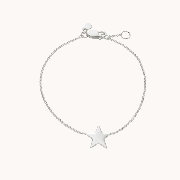 The stella star bracelet silver by bluboho is a delicate piece featuring a fine chain and a small, shiny star charm at its center. Crafted from sterling silver, it boasts a lobster clasp for fastening and an adjustable chain with an extra ring for size customization. The background is plain white.