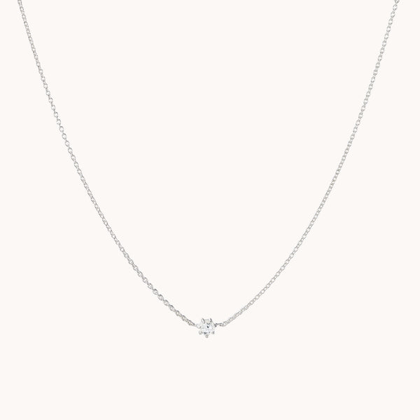 A delicate sterling silver chain necklace featuring a central white sapphire pendant. The pendant is simple and elegant, showcasing a single sparkling white sapphire that catches the light. The supernova white sapphire necklace from bluboho is displayed against a plain, light background.