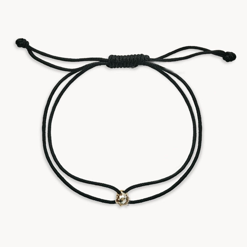 The supernova contemplation cord bracelet by bluboho features a minimalist black cord with an adjustable sliding knot closure. This elegant and simple bracelet is adorned with a single small 10k yellow gold bead at the center of the front.