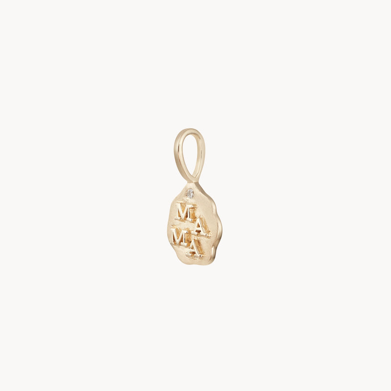 The mama charm by bluboho is a 10k yellow gold oval pendant with the word "MAMA" engraved vertically on a textured surface. Featuring a smooth loop at the top for attaching to a chain or necklace, this charming piece boasts a rustic and handcrafted appearance.