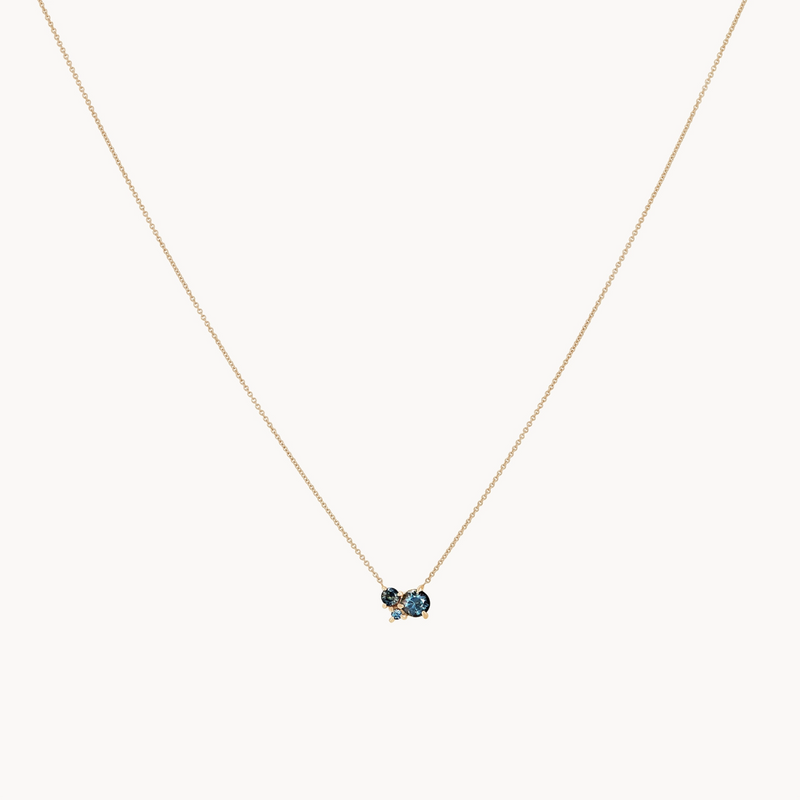 The "something blu tie dye moonchild ombre sapphire necklace" by bluboho is a delicate yellow gold chain featuring an elegant and minimalist design with three closely set blue sapphire stones.