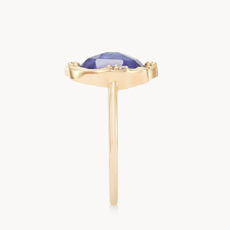 A tanzanite mood ring in 14k yellow gold from bluboho with a thin band featuring a large, faceted purple gemstone set in a prong setting. The ring is viewed from the side, showcasing the gemstone's height and the simple elegance of the band.