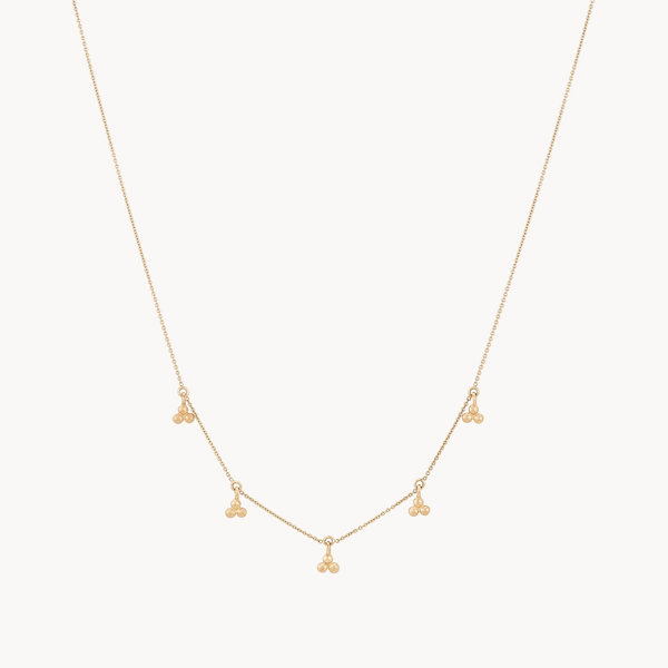 The bluboho abacus tripod necklace is a delicate gold piece featuring five small clusters of three tiny gold beads, evenly spaced along the chain. Its minimalist design offers an elegant and subtle accessory suitable for various occasions.