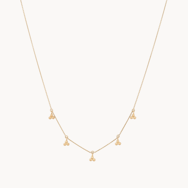 The bluboho abacus tripod necklace is a delicate gold piece featuring five small clusters of three tiny gold beads, evenly spaced along the chain. Its minimalist design offers an elegant and subtle accessory suitable for various occasions.