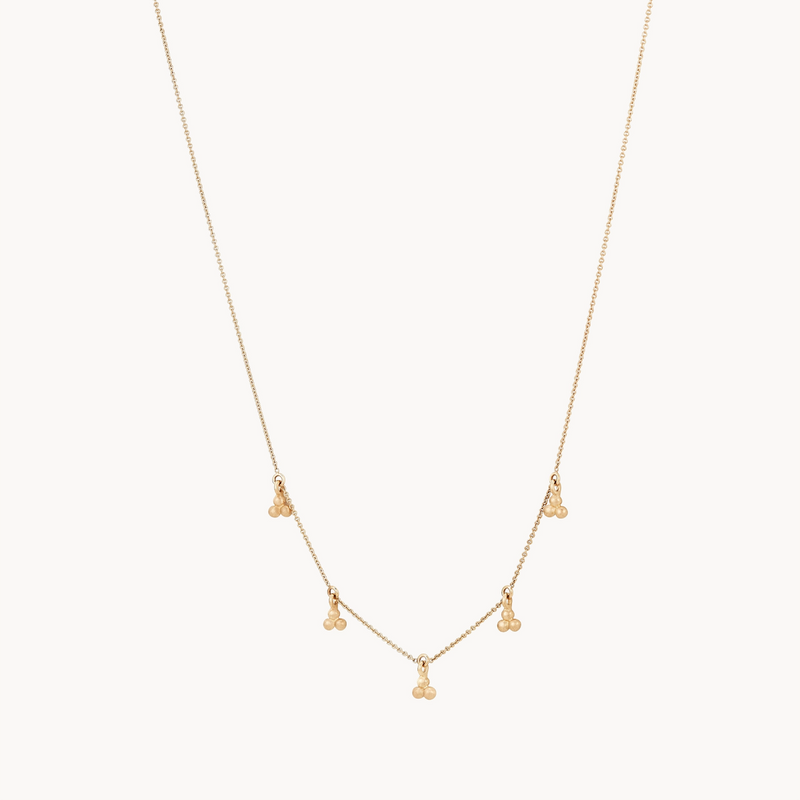 The bluboho abacus tripod necklace features a delicate gold chain adorned with five evenly spaced clusters, each boasting three tiny gold beads, creating a simple yet elegant design. The fine and lightweight chain is showcased against a plain white background.