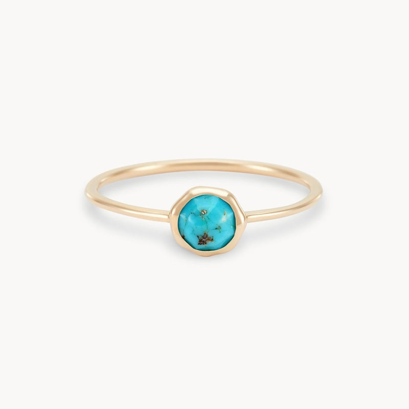 A delicate gold ring with a small, round turquoise stone set in the center. The turquoise features natural veining, adding character to its blue-green hue. The band is thin and polished, highlighting the vibrant center stone. This exquisite piece is the turquoise mini mood ring - 10k yellow gold, turquoise by bluboho.