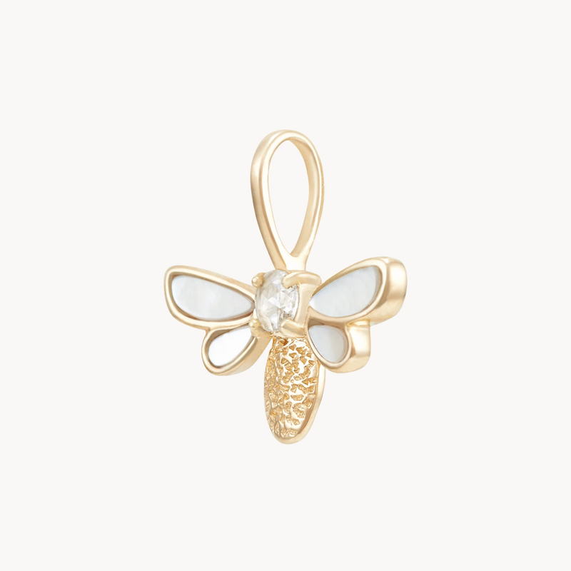 Introducing the honey glow bee charm by bluboho: a 10k yellow gold pendant featuring delicate mother of pearl inlay for its wings, a clear central gemstone, and a beautifully textured gold body. The integrated pendant loop at the bee's head allows it to be elegantly attached to any necklace, creating a sophisticated contrast against a plain white background.