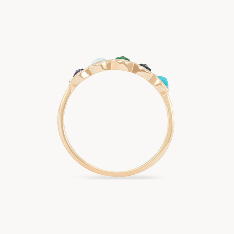 A close-up side view of the Coastal Nomad Five Stone Mood Ring by bluboho, featuring a delicate 14k yellow gold band with tanzanite, larimar, emerald, london blue topaz, and turquoise gemstones set along the top. The unevenly sized gems create an organic look against a white background.