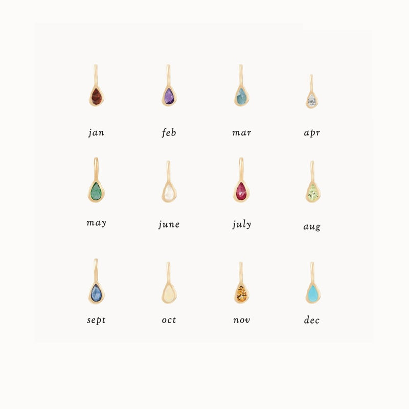 A set of gold pendants, each featuring a unique colored gemstone representing a birthstone for each month. From left to right, top to bottom: garnet (Jan), bluboho's pear amethyst February mood birthstone charm - 10k yellow gold (Feb), aquamarine (Mar), diamond (Apr), emerald (May), pearl (June), ruby (July), peridot (Aug), sapphire (Sept), opal (Oct), citrine (Nov), turquoise (Dec).