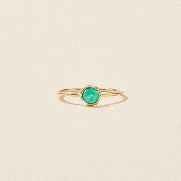 A delicate green chalcedony mini mood ring by bluboho, crafted in 10k yellow gold, featuring a vibrant round green chalcedony gemstone at the center. The thin band emphasizes the striking green stone, making it the focal point of the design. The ring is perfectly showcased against a plain, beige background.