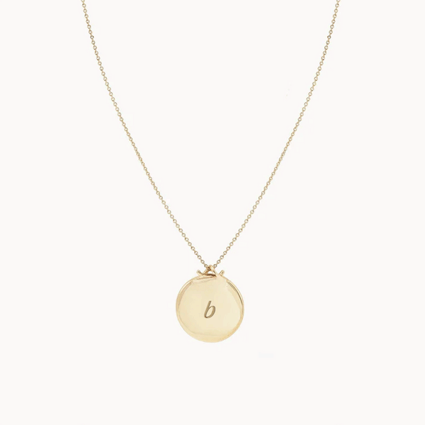 The Larger Imprint Forest Necklace by bluboho is a 14k yellow gold piece featuring a delicate chain and an engravable round pendant. The design is simple and elegant, showcased on a plain white background.