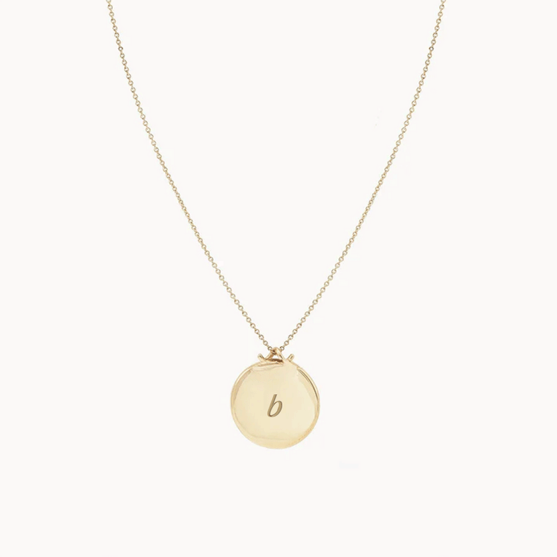The Larger Imprint Forest Necklace by bluboho is a 14k yellow gold piece featuring a delicate chain and an engravable round pendant. The design is simple and elegant, showcased on a plain white background.