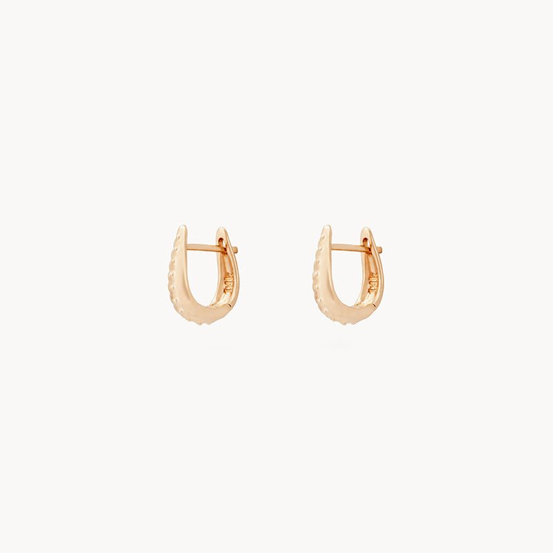 A pair of the restoration mini hoops - 14k yellow gold by bluboho, featuring a smooth, shiny finish and a rounded, slightly oblong shape. The earrings are presented against a plain white background.