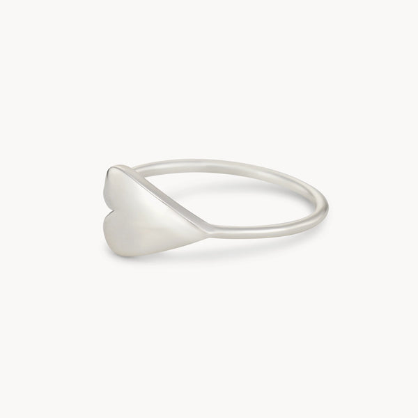 The bluboho Lovely Heart Sideways Ring Silver features a minimalist design with a smooth, heart-shaped detail on a thin, polished band. The heart sits horizontally, giving the ring a simple yet elegant look. Set against a plain white background, the ring's details are beautifully emphasized.