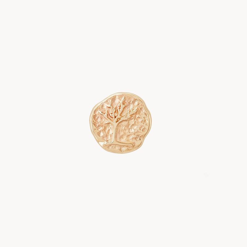 The tree of life stud earring from bluboho, crafted in 14k yellow gold, features an embossed image of a tree with bare branches in the center on a simple background. The stud’s textured design imparts a handcrafted, rustic charm.