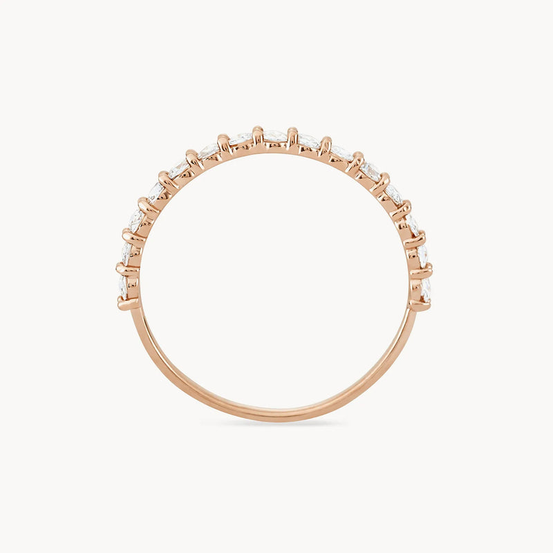 The Moonglade ring by beloved by bluboho is crafted from 14k rose gold and features a thin band adorned with small, evenly spaced white diamonds along the top half. Displayed on a white background, the ring's minimalistic yet elegant design shines beautifully.