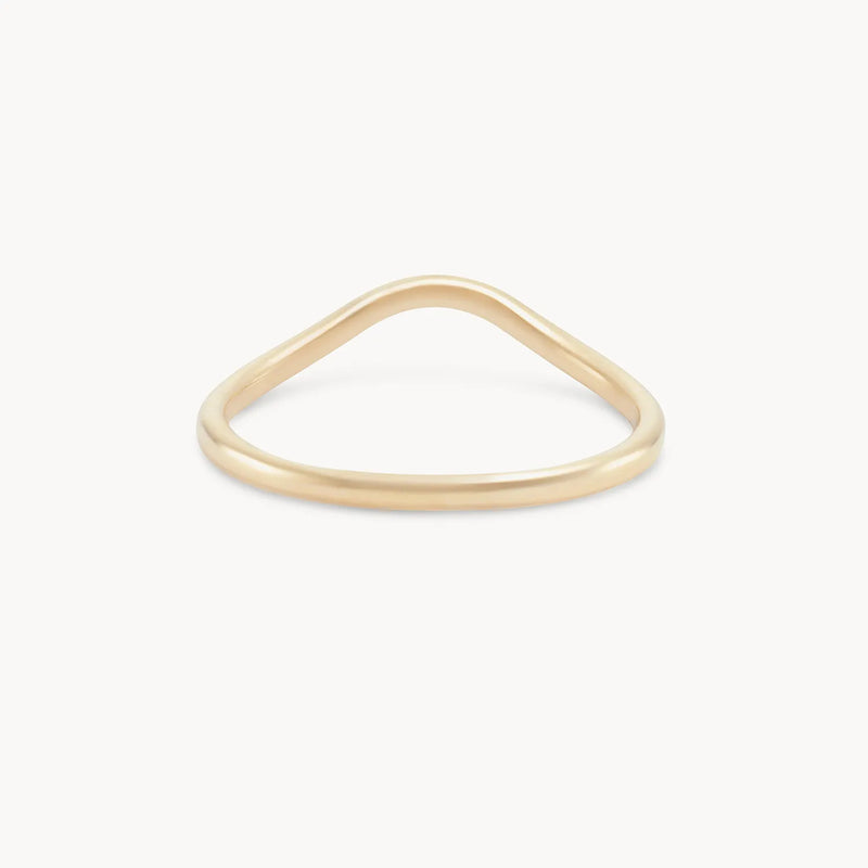 The "plain wave band - 14k yellow gold" by "beloved by bluboho" is a simple and elegant thin ring with a unique wave design, featuring a subtle curve that adds a modern touch. Displayed against a plain white background, the ring's minimalist and sophisticated appearance is perfectly highlighted.