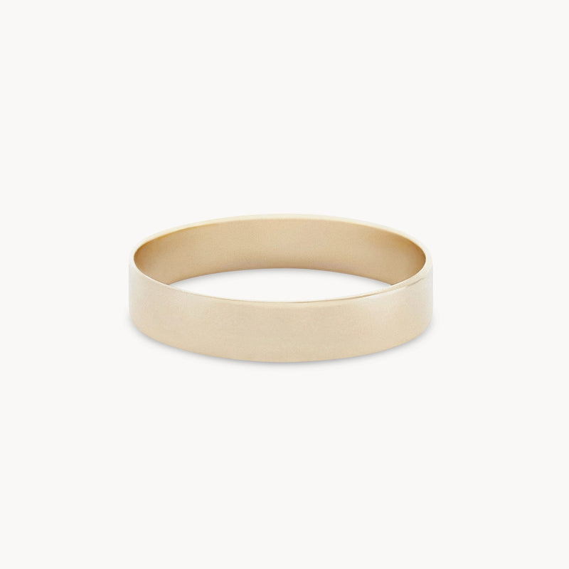 The Legacy Ring - 10k Yellow Gold from Bluboho is displayed against a white background, showcasing its smooth, polished finish and slightly rounded surface that lend it a sleek and elegant appearance. This minimalist gold ring is also engravable.