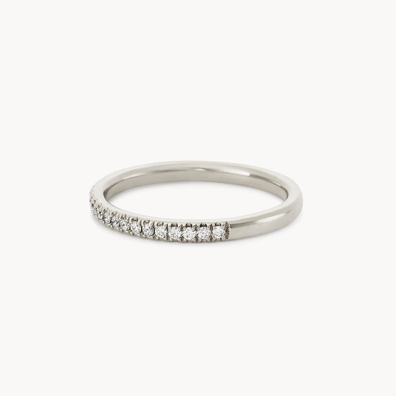 The Endalaus II ring by beloved by bluboho features a simple and elegant design in 14k white gold, adorned with small, sparkling white diamonds along the top half of the band. The diamonds are set in a neat, continuous row, giving the ring a timeless and luxurious appearance, with the bottom half of the band kept plain and polished.