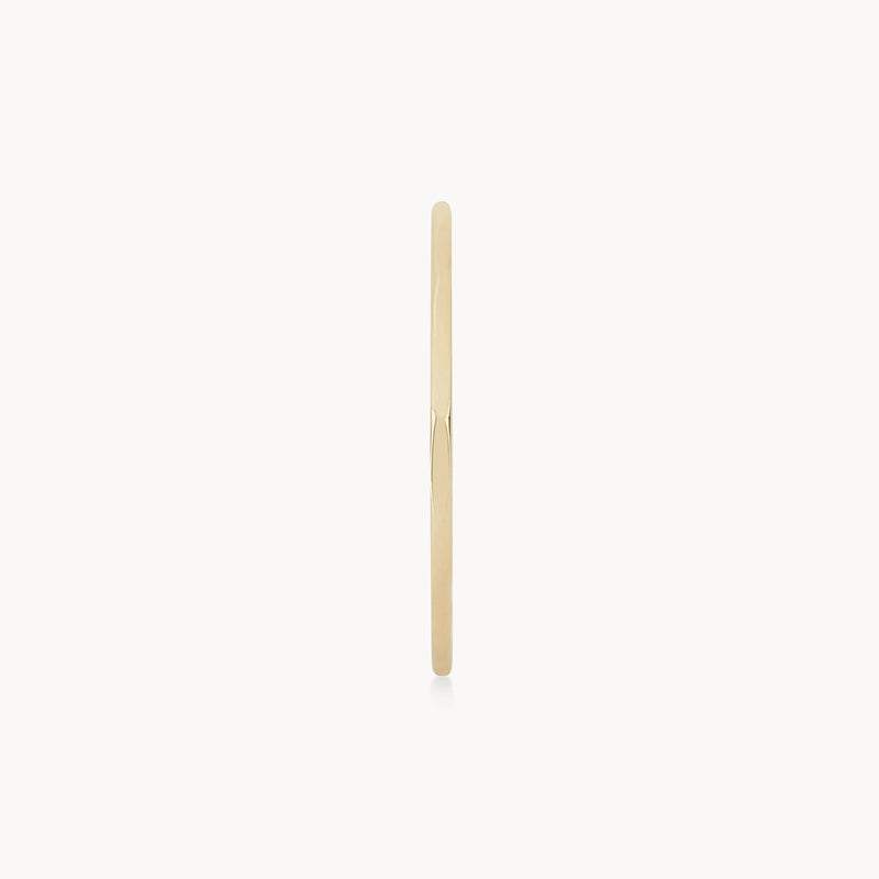 The Faceted Felicity Stacking Ring by bluboho, crafted from 10k yellow gold, is displayed from a side view against a white background. This minimalist ring exudes simplicity and elegance with its smooth and polished surface.