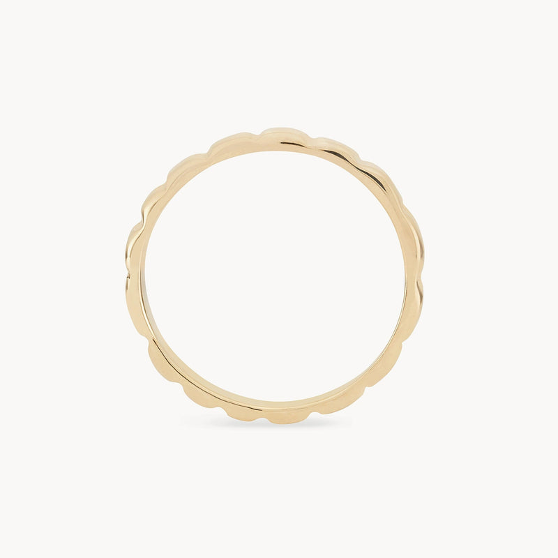 A thin, gold ring is shown against a white background. The peaks and valleys ring - 10k yellow gold by bluboho features a unique scalloped edge design, giving it a delicate and elegant appearance.